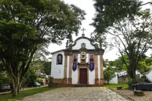 Igreja de Nossa Senhora do Rosário, em Tiradentes, entre árvores e com calçamento de pedra