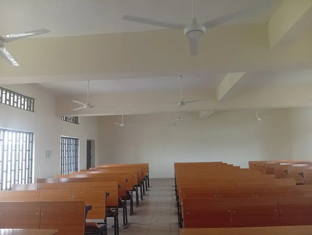 Sala de aula vazia com fileiras de carteiras de madeira