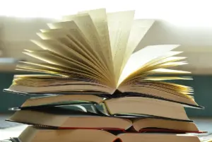 Livros empilhados com um deles aberto e as páginas em leque