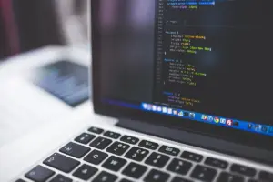 Notebook aberto com código de programação na tela, visto de lado