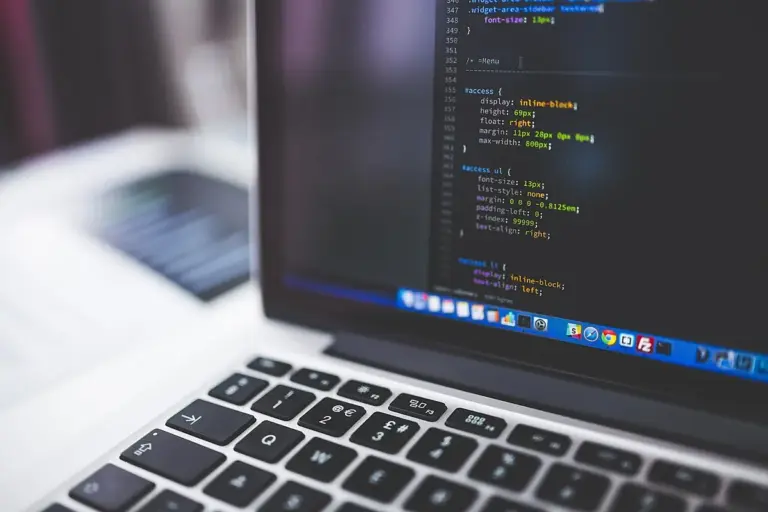 Notebook aberto com código de programação na tela, visto de lado