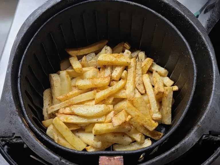 Batatas fritas temperadas no cesto de uma air fryer, vistas de cima