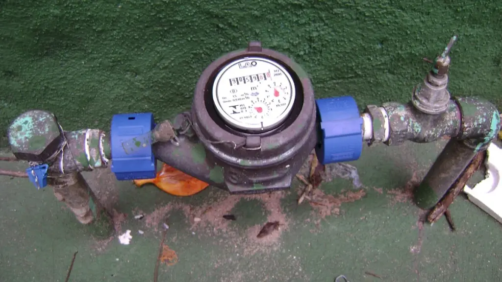 Hidrômetro conectado a uma tubulação junto a uma parede verde