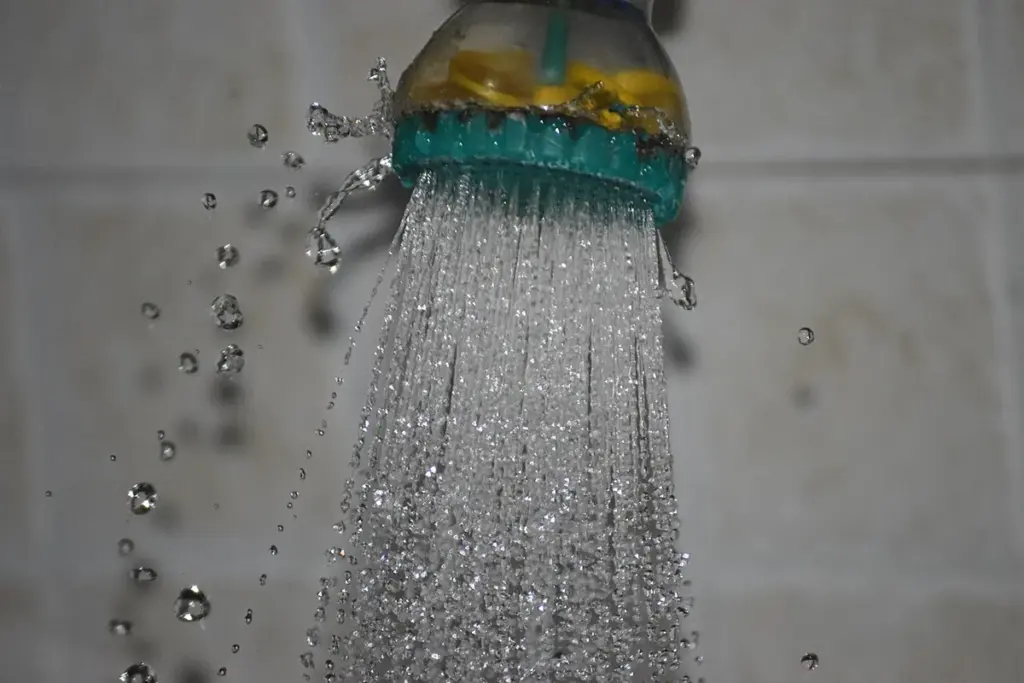 Jato de água saindo de um chuveiro, com as gotas congeladas pela câmera