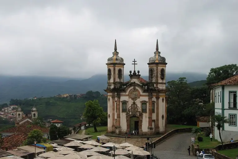 Igreja de São Francisco de Assis, em Ouro Preto, com casario e morros ao fundo em dia nublado