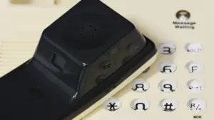 Fone preto sobre teclado de um telefone fixo claro