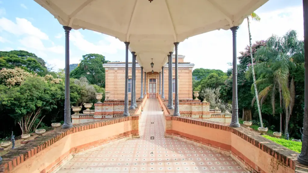 Passagem coberta com colunas no Museu Mariano Procópio, entre construção de tijolos e jardins, em registro de 2020